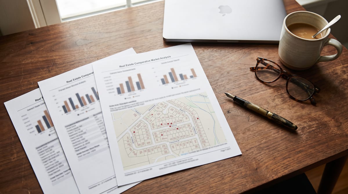 Printed comparative market analysis on a desk, with charts of recent sales and a map of a residential neighbourhood